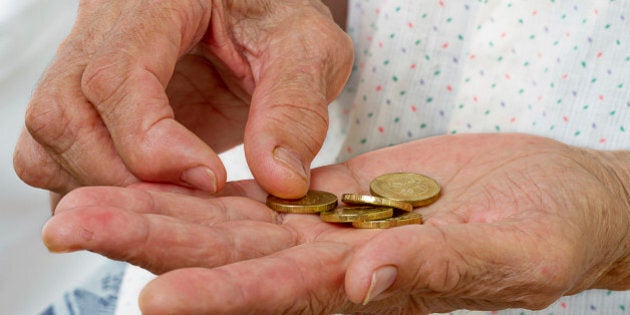 Hands of an old woman with five coins