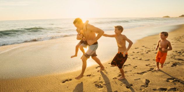 USA, California, Laguna Beach, Father playing football on beach with his three sons (6-7, 10-11, 14-15)