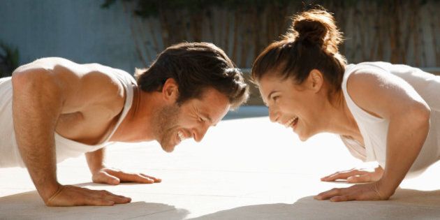 Man and woman laughing while doing push-ups