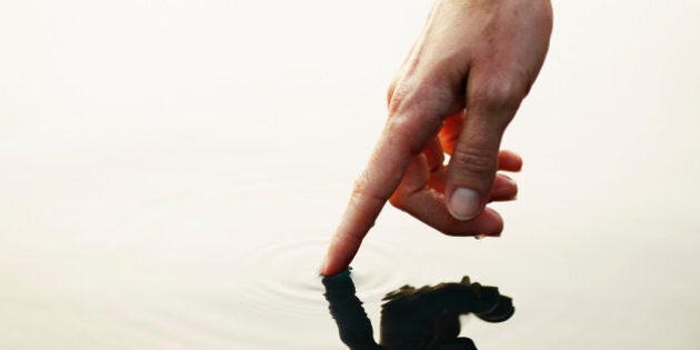 Finger touching surface of water