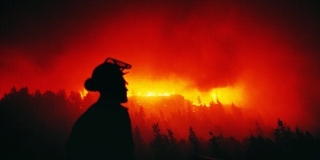 Firefighter Looking at a Forest Fire at Night