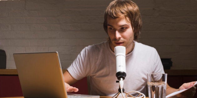 Young man with laptop and microphone, indoors