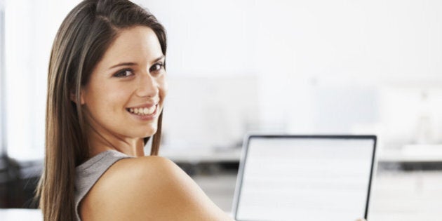 Portrait of an attractive young woman sitting at a desk with a laptop in front of her