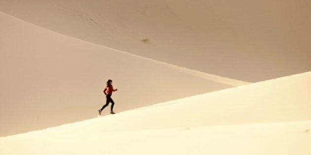 A women running on the sand dunes.