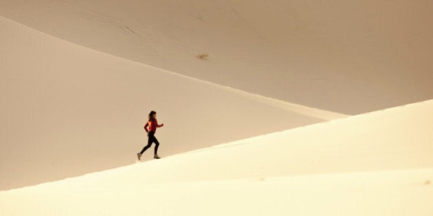 A women running on the sand dunes.