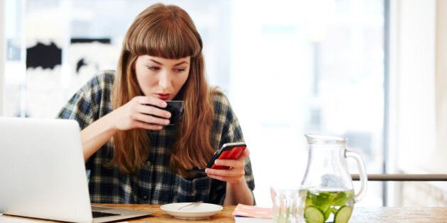 Girl drinking coffee checking her phone