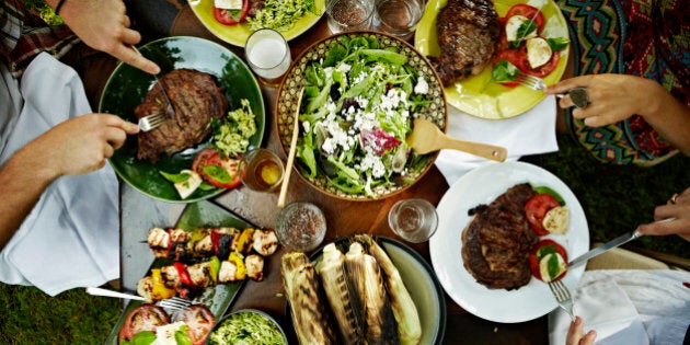 Overhead view of friends dining at table with food in backyard garden