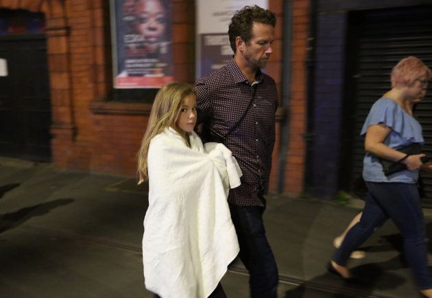 A young girl and a man leave the Manchester Arena, where 19 people died in an explosion.
