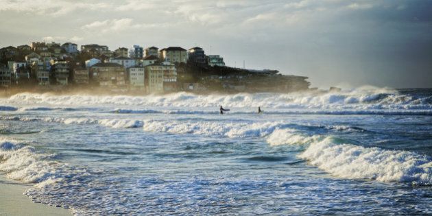 Bondi Beach, Sydney, Australia, on a fine winter morning with good surf, two surfers just walking out into the waves.