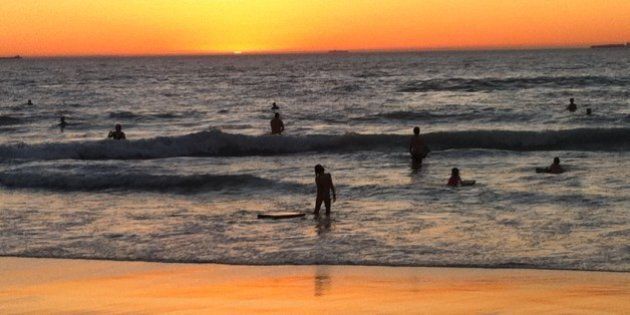 Swimmers and bodyboarders enjoy the water late at dusk during a Perth summer heatwave.
