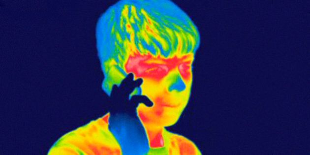 Thermogram of a male teenager talking on a cell phone. The temperature scale runs from white (warmest) through red, yellow, green and cyan, blue and black (coldest).