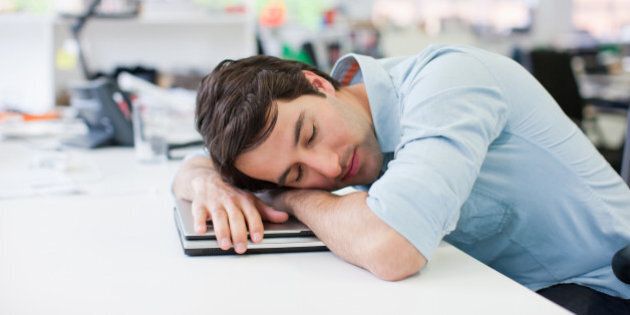 Businessman sleeping on laptop at desk in office