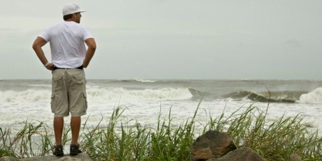 A surfer looks out over the Atlantic Ocean as the first bands of rain and wind from Hurricane Irene come ashore causing larger than normal waves at Folly Beach in Charleston, S.C., Friday, Aug. 26, 2011. (AP Photo/Brett Flashnick)