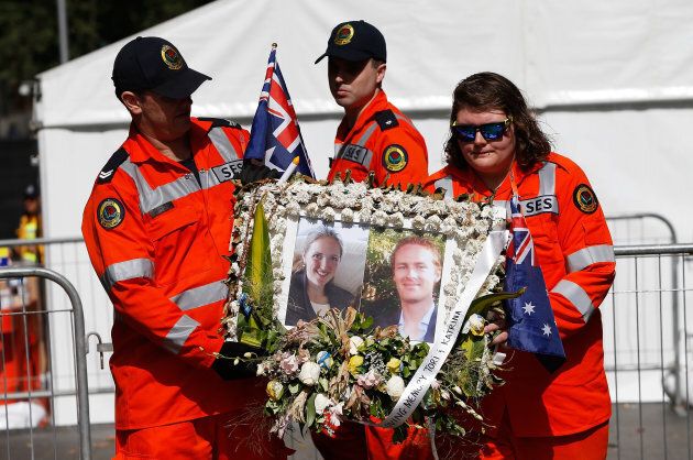 Volunteers from the State Emergency Services carry a picture of Tori Johnson and Katrina Dawson, victims of the siege at Martin Place, at the memorial site.