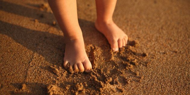 Small feets of child on sandy beach