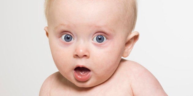 Portrait of expressive baby with wide surprised eyes and mouth open looking at camera