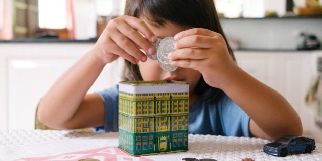 A child places Australian coins into a piggy bank