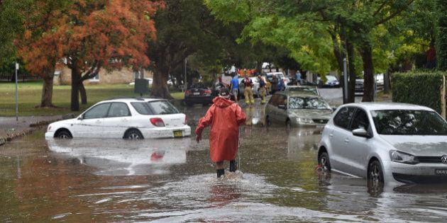 A worker wades past inundated cars on a flooded street after a storm in the eastern suburbs of Sydney on December 16, 2015. Sydney was smashed by a tornado-like storm with hail as big as golf balls and winds gusting at 200 kilometres (124 miles) an hour causing havoc with two people requiring treatment -- one for shock and one for a head wound -- in the hardest-hit suburb of Kurnell, an ambulance official said. AFP PHOTO / Peter PARKS / AFP / PETER PARKS (Photo credit should read PETER PARKS/AFP/Getty Images)
