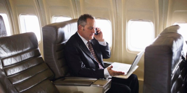 man wearing suit using cell phone on airplane