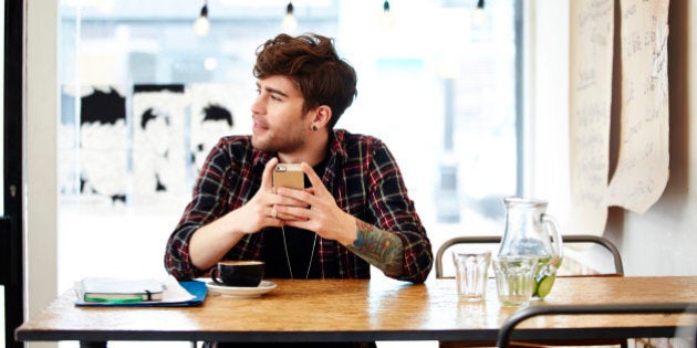 Guy with phone relaxing in coffee shop