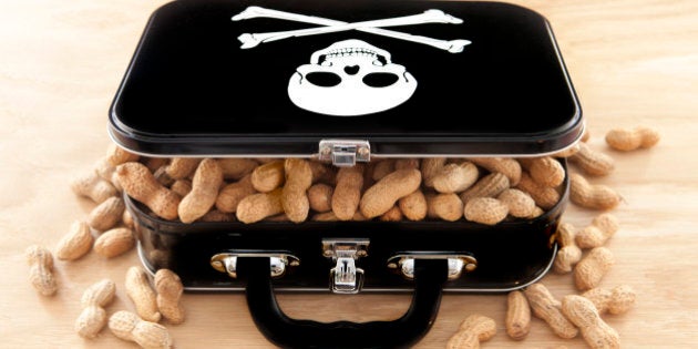 Black lunchbox with skull and crossbones on lid and peanuts overflowing out of container