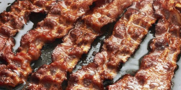 Bacon slice being cooked in frying pan. Close up.