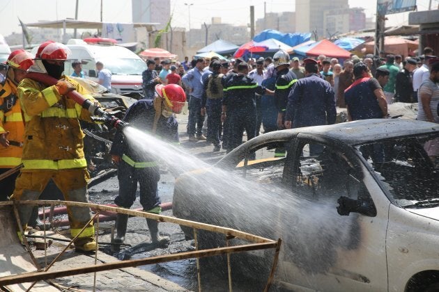 Firefighters work to extinguish the wreckage following a car bomb attack near a government office in the Karkh district of Baghdad on Tuesday.