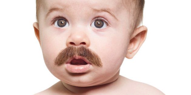 Portrait of expressive baby with mustache looking above camera