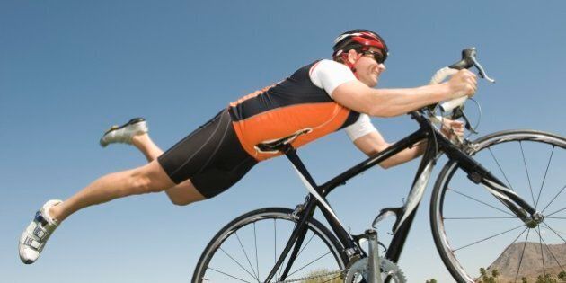 Male cyclist balances his stomach on bicycle seat
