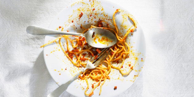 Dirty bowl with pasta leftovers with spoon and fork