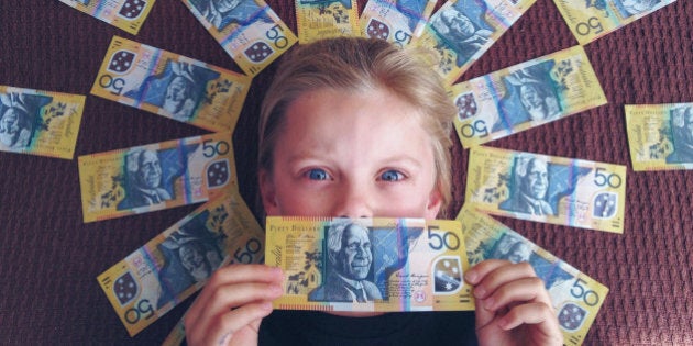 Child holding onto and surrounded by large amount of Australian money