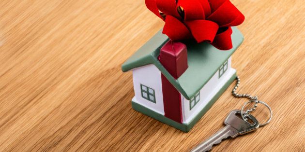 house with red ribbon and key on wooden background