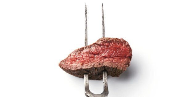 Piece of beef steak on meat fork on white background