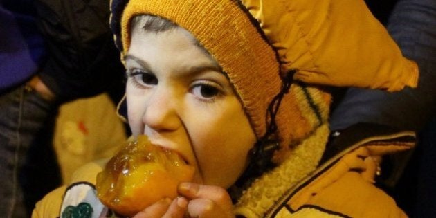 A Syrian child eats a fruit on the outskirts of the besieged rebel-held Syrian town of Madaya, on January 11, 2016, after being evacuated from the town.Dozens of aid trucks headed to Madaya, where more than two dozen people are reported to have starved to death, after an outpouring of international concern and condemnation over the dire conditions in the town, where some 42,000 people are living under a government siege. / AFP / LOUAI BESHARA (Photo credit should read LOUAI BESHARA/AFP/Getty Images)