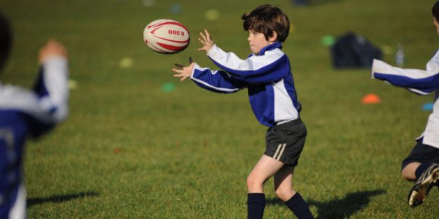 Young boy receiving a pass in a rugby training session on a grass pitch