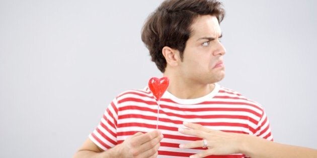 Upset man in red striped shirt with heart lollipop