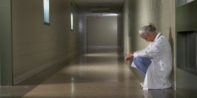'Female doctor sitting in hospital corridor, side view'