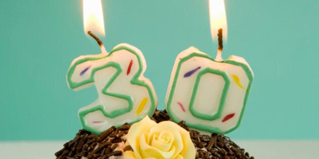 Chocolate cupcake with sprinkles and lit candles indicating number 30