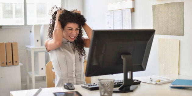 Mixed race businesswoman frustrated at computer at desk in office