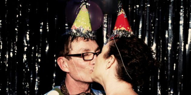 A mature couple kissing at a party