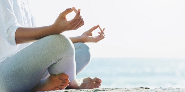 A young woman performing a yoga routine on the beach in the summer sun