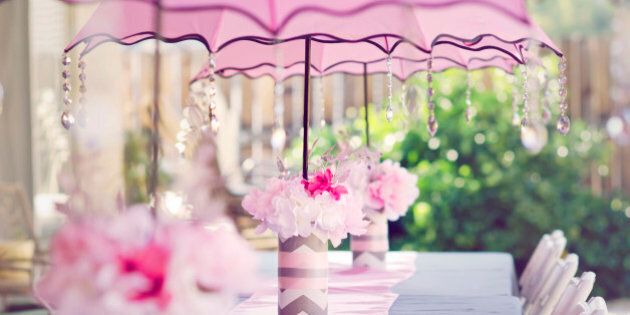 Table set for a baby shower for a girl. With pink umbrellas with crystals and pink flowers.