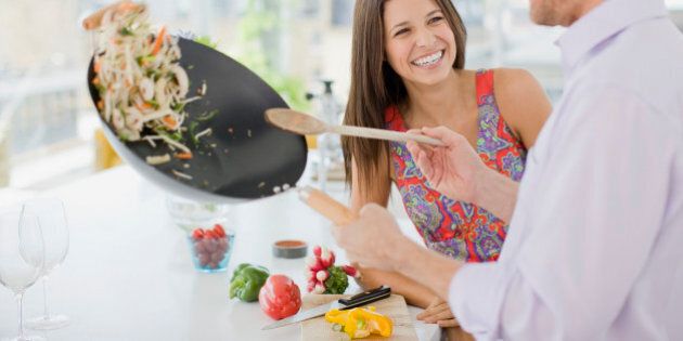Woman watching husband flipping stirfry in the kitchen