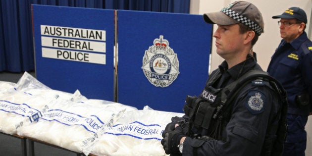 Police officers stand guard over methamphetamine seized by the Australian Federal Police in Sydney, Friday, May 15, 2015. A Hong Kong man has been charged with the importation of the 150 kilogram (330 pound) haul that police say has a potential street value of up to $100 million (US $80.65 million). (AP Photo/Rick Rycroft)