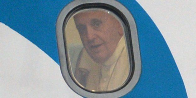 Pope Francis peers from the window of his plane shortly after arriving at a military airbase in Manila on January 15, 2015. Pope Francis will immerse himself January 15 in the Catholic Church's passionate and chaotic Asian heartland as he lands in the Philippines for a five-day trip that is tipped to attract a world-record papal crowd. AFP PHOTO/TED ALJIBE (Photo credit should read TED ALJIBE/AFP/Getty Images)