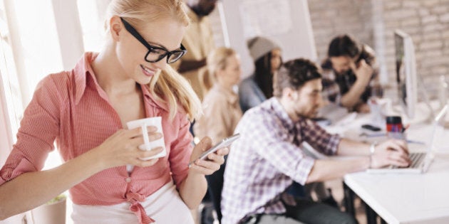 Close up of a young woman using smart phone while working in the office