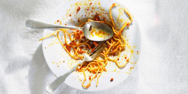 Dirty bowl with pasta leftovers with spoon and fork