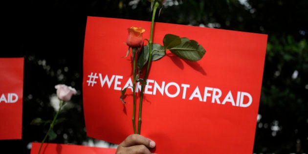 An activist holds a poster during a rally condemning Thursday's attack, outside the Starbucks cafe where it took place in Jakarta, Indonesia, Friday, Jan. 15, 2016. Indonesians were shaken but refusing to be cowed a day after a deadly attack in a busy district of central Jakarta that has been claimed by the Islamic State group. (AP Photo/Dita Alangkara)