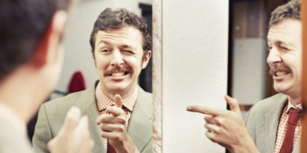 Man pointing at reflection in mirror