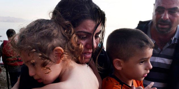 KOS, GREECE - AUGUST 15: A Syrian family arrives at a beach on the Greek island of Kos after crossing a part of the Aegean sea from Turkey to Greece in a dinghy on August 15, 2015 in Kos, Greece. The Greek government has sent a cruise ship to the island of Kos which will be able to house up to 2,500 refugees and operate as a registration centre, after 2,000 Syrian refugees were locked in an old stadium during a registration process and left without water for more than a day. (Photo by Milos Bicanski/Getty Images)